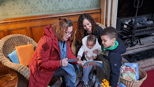Volunteers read a book to a family